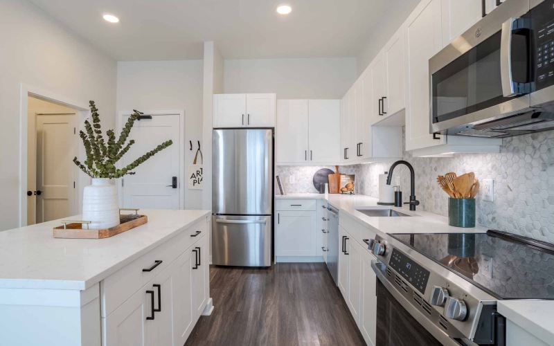 kitchen with dark flooring and white cabinetry with white quartz